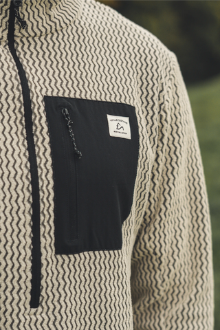 Atmungsaktiver beiger Half Zip Skirolli für Herren mit Brusttasche. Idealer Midlayer von The Clue Clothing für kalte Tage auf der Piste.