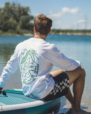 Weißer Longsleeve für Sie und Ihn mit grünem Brust und Backprint von The Clue Clothing beim Surfen.