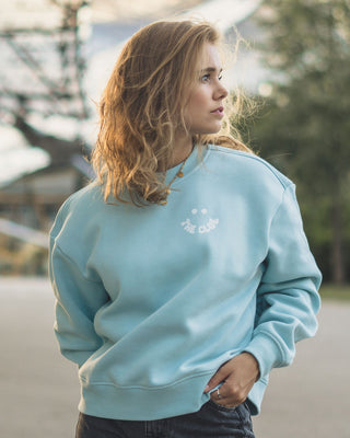 Leichter Damen Pullover ohne Kapuze in Ocean Blue. Das Hellblaue Sweatshirt mit Smile Brustdruck in der Natur getragen.